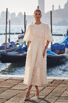 a woman in a white dress standing on a pier