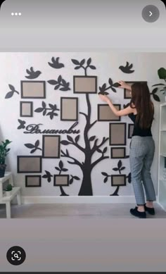 a woman is painting a family tree on the wall