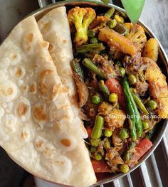 a bowl filled with food next to a pita bread on top of a table