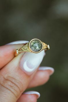 Product Details Ring Style: The "Selene" is an accented-style moss agate women's engagement ring. Many other center stone options are available upon request. Center Stone: 7mm Round Cut Moss Agate Materials: 14K gold engagement ring featuring a moss agate center stone Customizable: Because each ring is handcrafted to order, we can customize yours using unique materials, gemstones, or design features, often without any added cost! We can even use personal materials that you send! Basic ... Untraditional Unique Engagement Rings, Bohemian Wedding Rings Melanie Casey Fine Jewelry, Affordable Classic Wedding Crystal Ring, Emerald Stone Cottagecore Engagement Ring, Earthy Engagement Rings Moss Agate, Stone Settings Ring, Non Conflict Engagement Rings, Non Traditional Engagement Rings Inexpensive, Not Shinny Engagement Ring