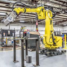 an industrial factory with robotic arms working on equipment in the process area, while another robot stands nearby