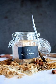 a glass jar filled with spice mix next to a spoon on top of a table