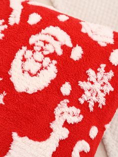 a red and white pillow on top of a bed next to two pillows that have snowflakes on them