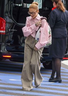 a woman with glasses is walking across the street