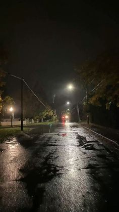 a street at night with the lights on and cars parked in the middle of the road