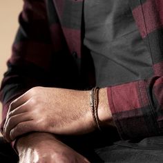 a man wearing a red and black checkered shirt is typing on his laptop computer