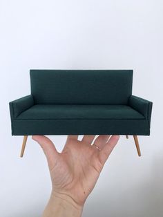 a person holding up a miniature couch in their hand