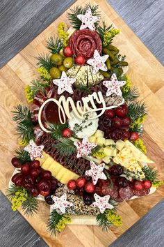 a christmas tree made out of cheese and fruit on a cutting board with the word merry spelled in cursive