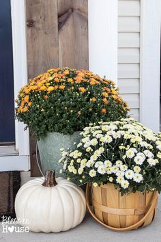 two buckets filled with flowers sitting next to each other on the front step of a house