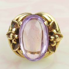 A wonderful translucent 4.3 carat light purple amethyst gem tops this vintage 14k yellow gold statement ring. Large flowers and crescent shapes frame the 14.7mm x 9.2mm x 4.5mm cabochon. The oval gem has nice translucent light violet luminous color with some natural visible crystal structure. The ring has a 1/2 inch tall profile with deep gold wire gallery. It was finished with thick sturdy split shoulders and a 2.8mm wide shank band. The ring measures an approx. size 6 and could be re-sized by an experienced jeweler. The recently cleaned vintage setting is in very good condition with minor surface wear. Please see photos for condition and detailed measurements below. This piece would make a lovely February birthstone gift. Wt: 6.1 grams US Ring size : 6 Length: 15mm or 5/8 Inch Width: 18m Vintage Amethyst Cabochon Jewelry, Vintage Purple Oval Cabochon Jewelry, Vintage Amethyst Ring Stamped 14k, Vintage Purple Amethyst Ring Stamped 14k, Vintage 14k Amethyst Ring, Purple Cabochon 14k Gold Jewelry, Vintage 14k Gold Purple Jewelry, Vintage Purple 14k Gold Jewelry, Vintage Lavender Jewelry For Formal Occasion