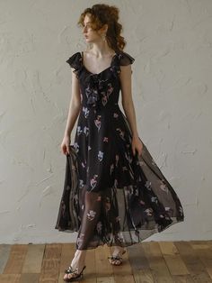 a woman in a black dress standing on a wooden floor