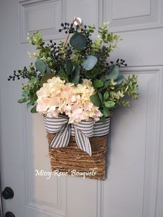 a basket with flowers hanging on the front door