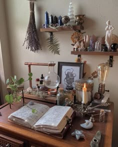 an open book sitting on top of a wooden table next to a candle and other items