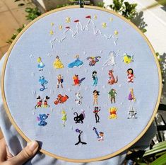 someone is holding up a cross - stitch embroidery kit with many different characters on it