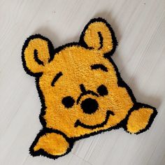 a winnie the pooh shaped rug on top of a white wooden floor with black trim