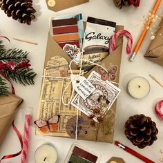 an assortment of christmas cards and candles on a table with pine cones, candy canes and other holiday decorations