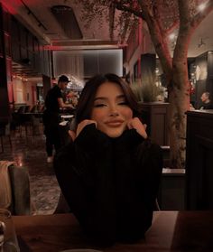 a woman sitting at a table with her hands on her face in front of the camera