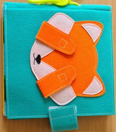 an orange and white animal is on top of a blue book with scissors next to it