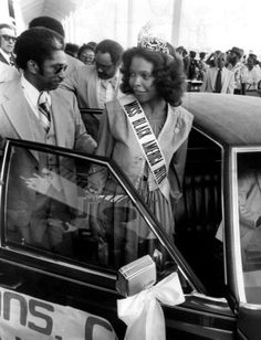 an old black and white photo of two people standing next to a car with the door open