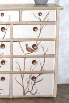 a white dresser with birds painted on it's drawers and some brown knobs