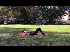 a woman laying on top of a pink mat in the grass next to a tree