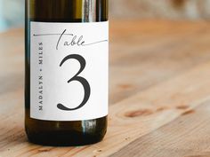 a bottle of wine on a wooden table with a label that says table 3 and the number three