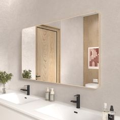 a bathroom with two sinks and a large mirror over it's sink, in front of a white wall