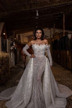 a woman in a white gown standing on a brick floor with her hands on her hips