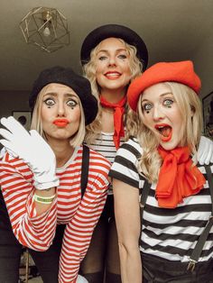 three women dressed in costumes posing for the camera with their mouths open and hands up