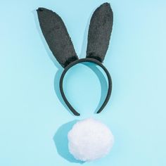 an overhead view of a black bunny ears headband with a white ball on it