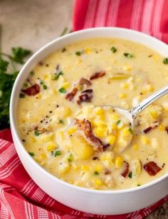 a white bowl filled with corn and cheese soup on top of a red napkin next to a spoon