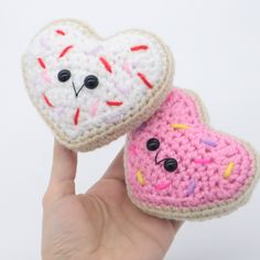 two crocheted heart shaped donuts with sprinkles are held up to the camera