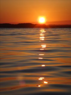 the sun is setting over the ocean with water