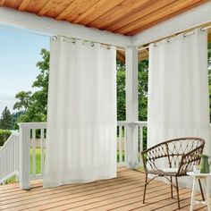 an open porch with white curtains and wicker furniture on the wooden decking area