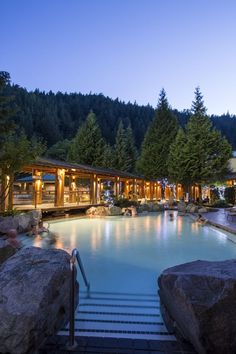 an outdoor swimming pool surrounded by rocks and trees with the words quick escape harrison hot springs