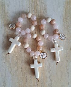 These beautiful high quality handmade mini rosaries are perfect as favors for any religious occassion  *Baptism *First Communion *Confirmation  *Wedding *Graduation Gift *Funeral memorial  *Teachers gift Each mini rosary is made using * 8mm sunstone beads *8mm rose quartz beads *8mm matte fossil jasper beads *1 8mm faceted clear glass bead *20x30mm howlite cream cross  *nylon thread *enamel with gold plate letter charm *Each mini rosary measures approx 3 inches in length.  *White organza bags are available upon request  *You can order 1 or multiple, bulk is already discounted. Don't see the quantity you need? Please message me  *Other gemstone options available  *processing time 1 to 3 days  *Arrives to US within 5 to 7 business days.  *Within Canada 7 to 10 business days. You can message Handmade Cross Rosary For First Communion, Handmade Adjustable Rosary For First Communion, Handmade Rosary Bracelet With Round Beads For Baptism, Mini Rosary Beads, Handmade White Rosary For Baptism, Handmade Rosary With Round Beads For Baptism, Personalized Rosary With Round Beads As Gift, Pink Cross Bracelet For Gift, Pink Cross Bracelet For Gifts