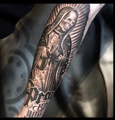 a person with a tattoo on their arm holding a cross and a skull in the middle