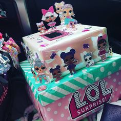 there is a pink and green box with littlest pet dolls on it sitting in the car