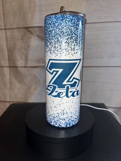 a blue and white tumbler sitting on top of a black table next to a wall