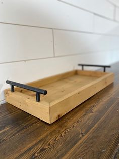 a wooden tray sitting on top of a hard wood floor next to a white wall