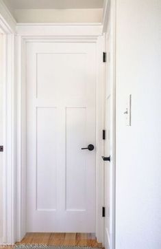 a white door is open in an empty room with wood floors and rugs on the floor