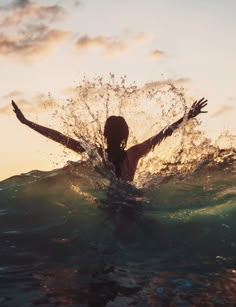 a woman standing in the water with her arms outstretched