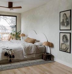 a bed sitting in a bedroom next to a window with pictures on the wall above it