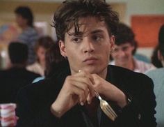 a young man sitting at a table with a wine glass in his hand