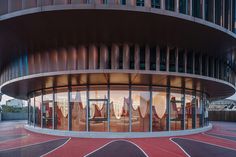 the circular building has many windows and red carpeted flooring in front of it