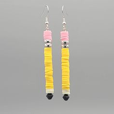 pair of earrings with yellow, pink and white beads on grey background in studio shot