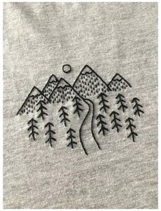 an embroidered t - shirt with mountains and trees on it