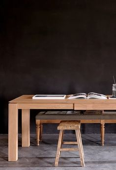 a wooden table with two stools and an open book on it's side