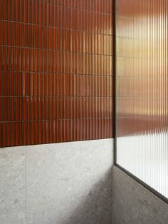 the wall is made out of red and white tiles, which are lined with thin strips of wood