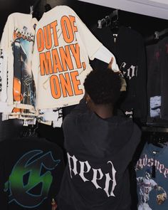 a man is looking at shirts hanging on the wall in a room with other items